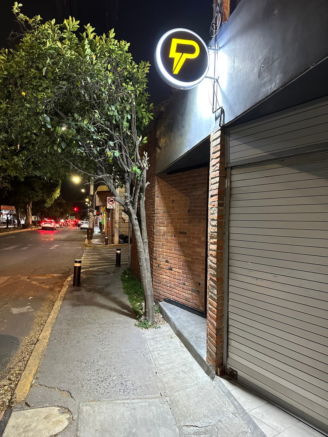 Front of Jardines, with the lit FitPOD logo on the brick wall