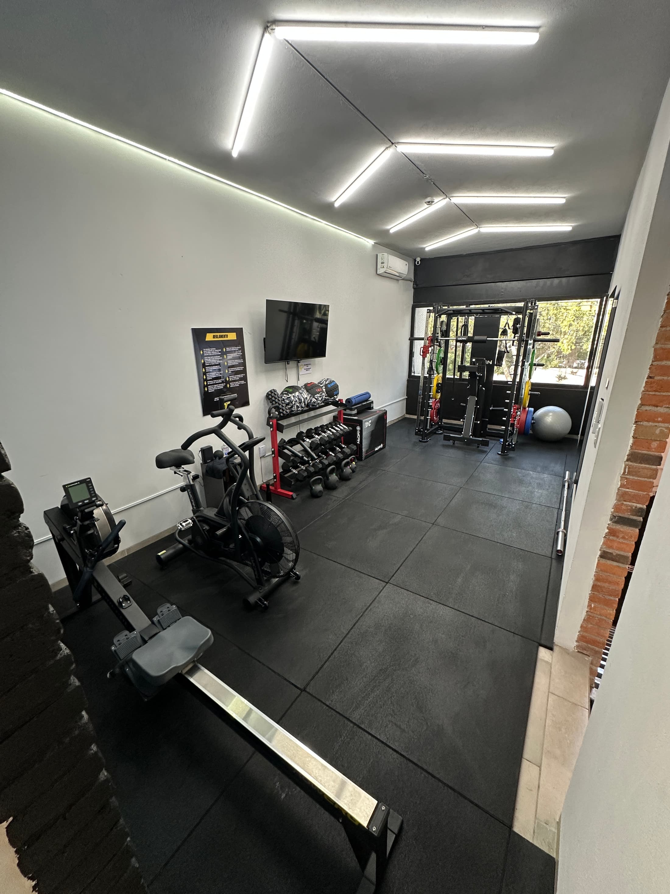 Real interior of FitPOD Jardines: rower, air bike, dumbbells and multifunctional rack
